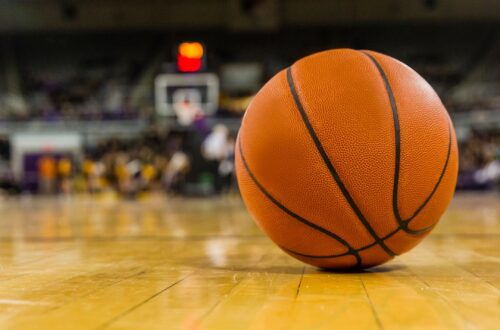 Orange basketball on court with basketball goal in background. blurred